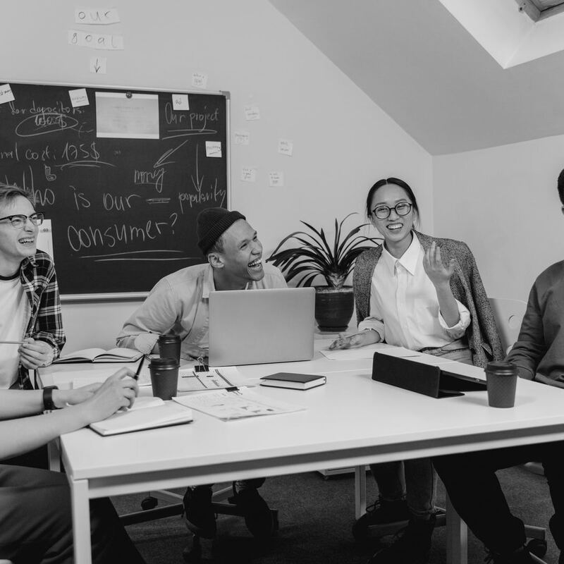 Sales team reviewing a consumer strategy around a meeting table, in black and white