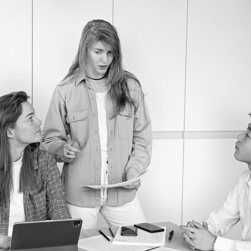 Team member coaching two colleagues during a training session, in black and white