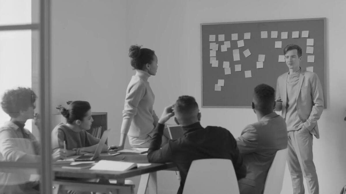 A business team meeting with a presenter in a bright office, in black and white
